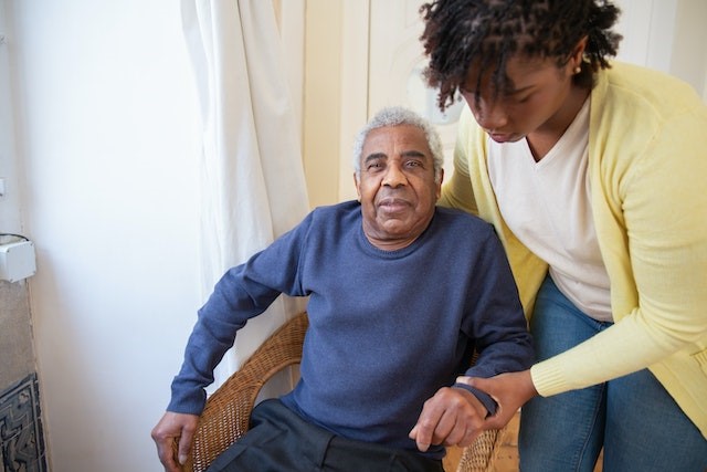 Young person helping elderly person into chair